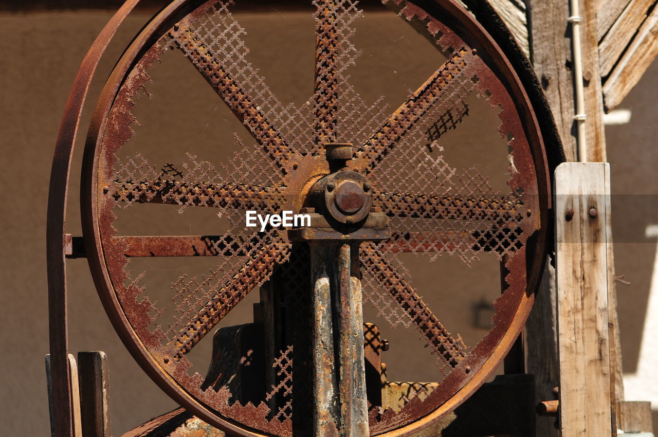 Close-up of rusty wheel against old building