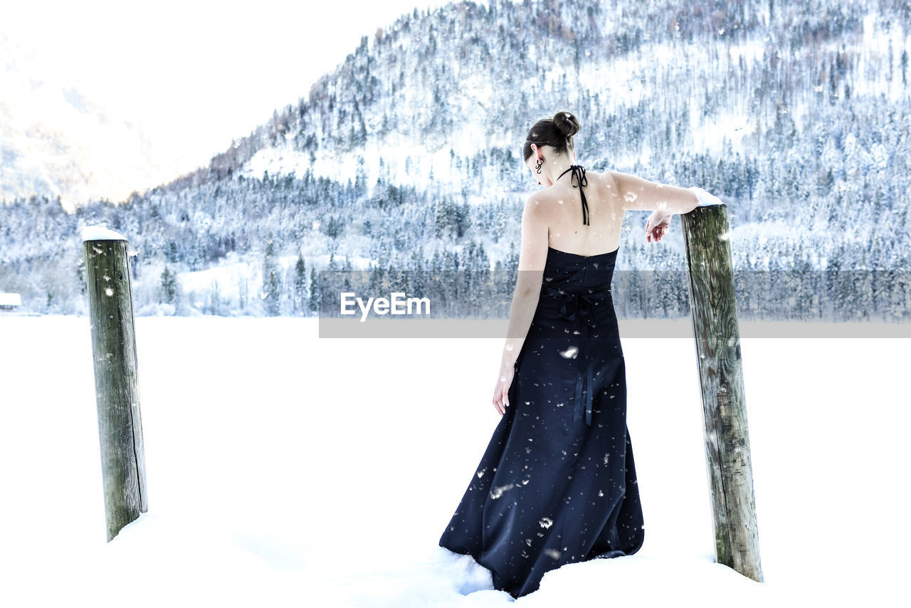 Woman standing on snow covered field against mountain