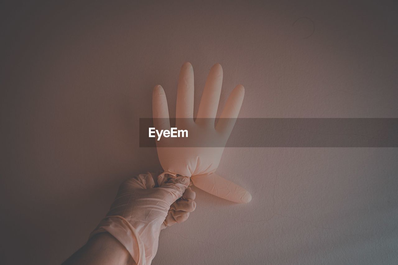 Cropped hand of woman gesturing against wall