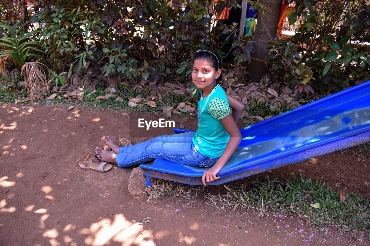 Portrait of smiling girl sitting on slide outdoors