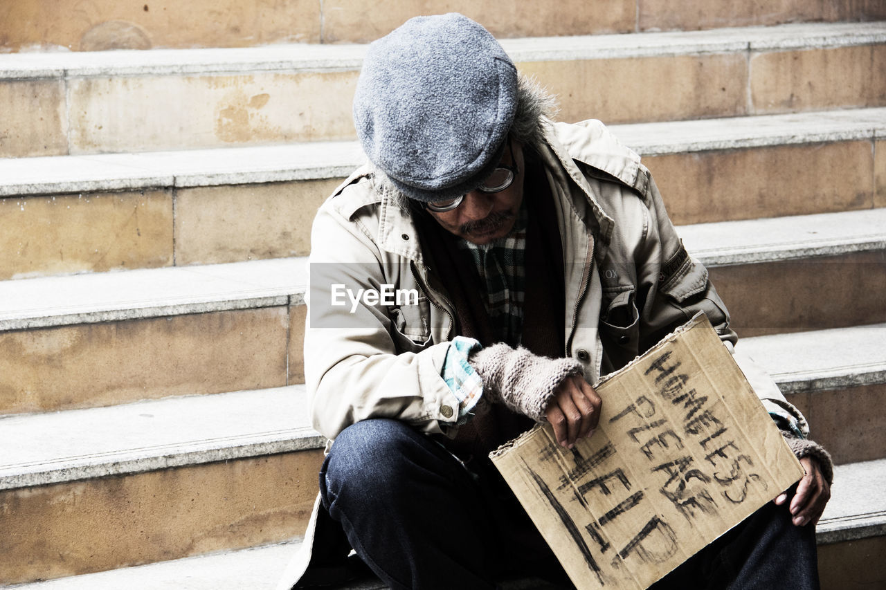 Male beggar begging while sitting on steps
