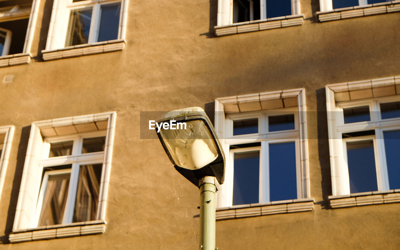 Low angle view of streetlight by building with closed window