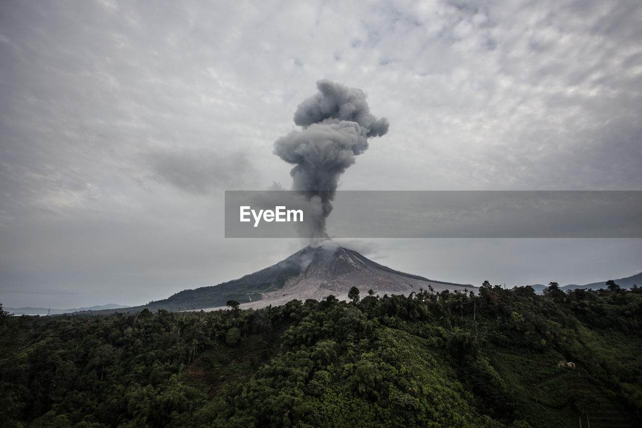 Scenic view of smoke emitting from volcanic crater against sky
