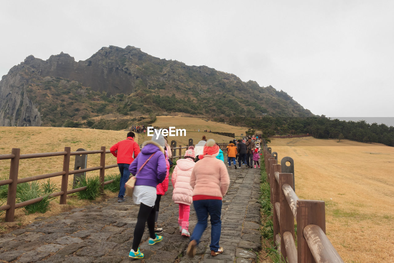 REAR VIEW OF PEOPLE WALKING ON LANDSCAPE