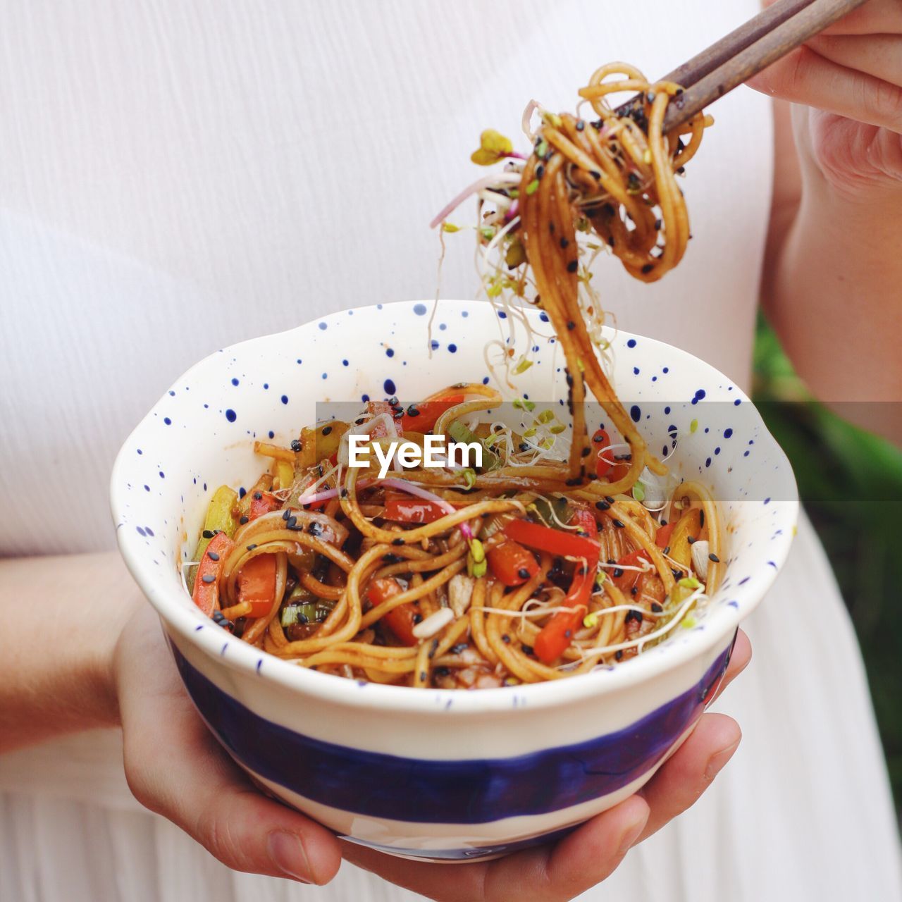 Midsection of woman holding noodles using chopsticks