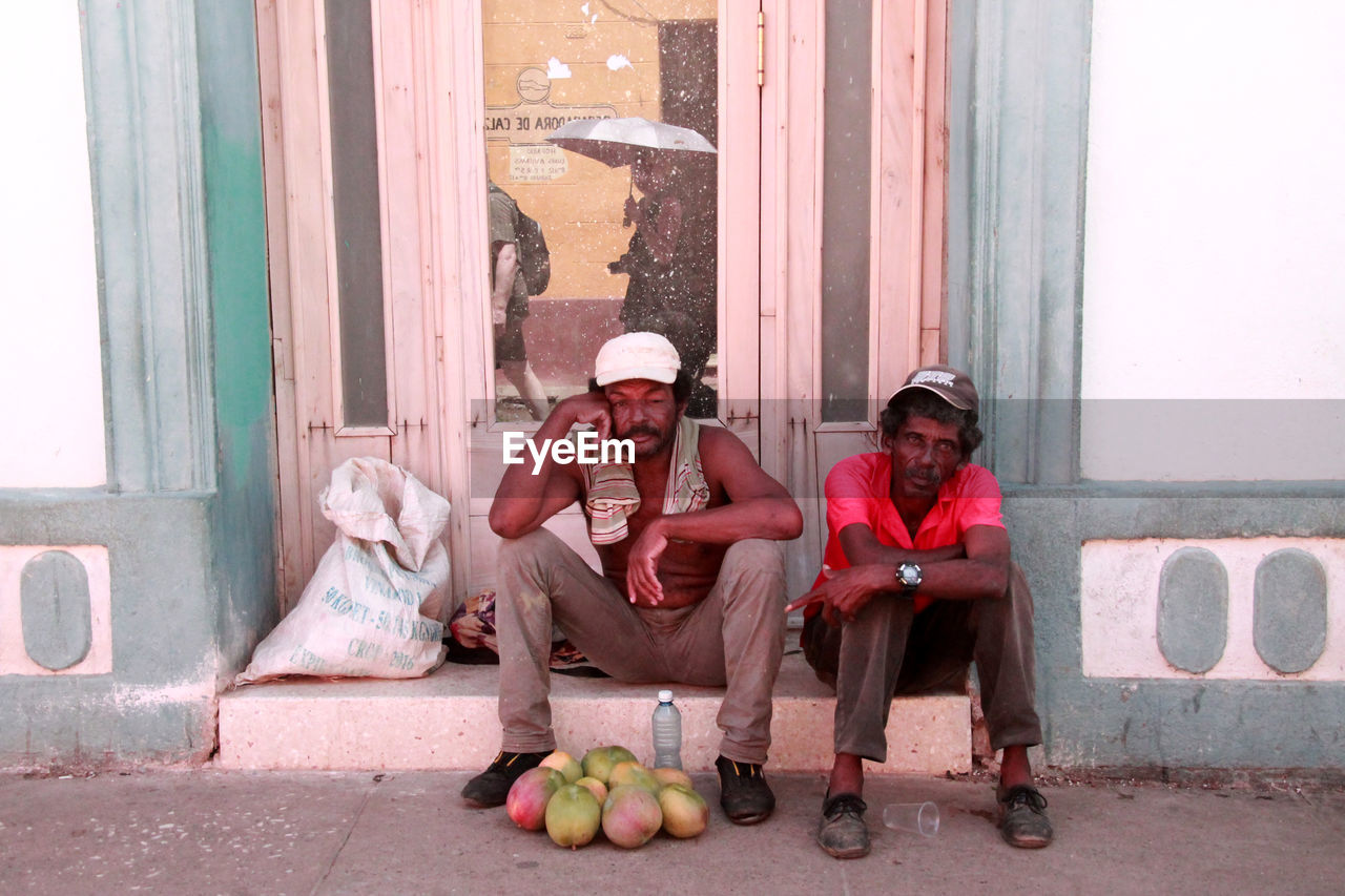 FULL LENGTH OF FRIENDS SITTING ON CITY STREET