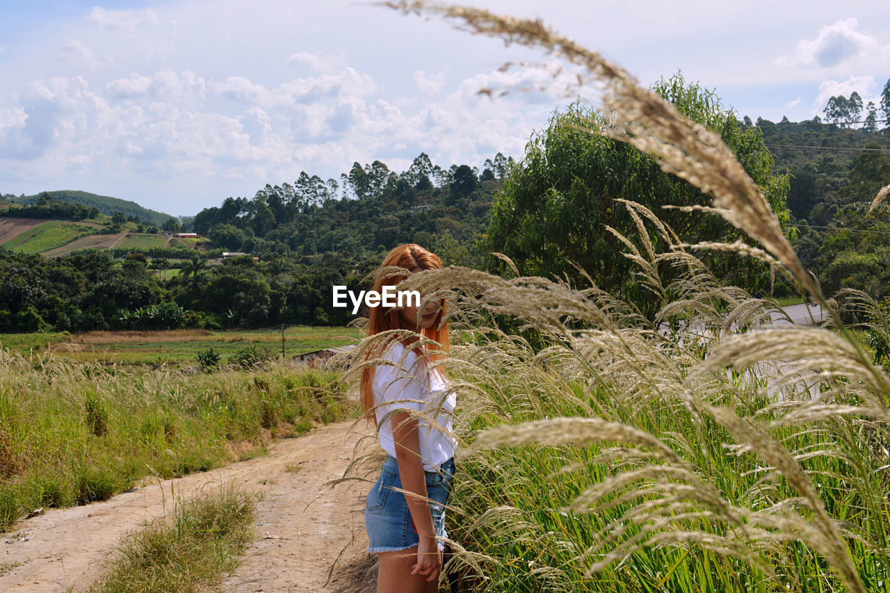 Side view of young woman standing at field