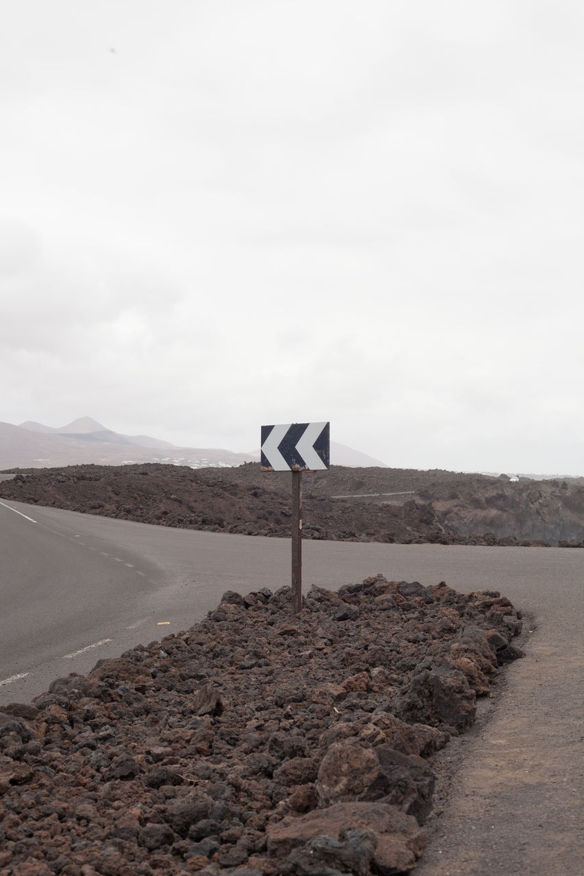 SIGN ON ROAD BY LAND AGAINST SKY