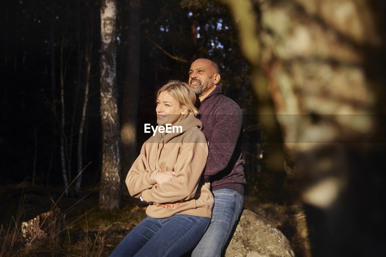 Couple resting in forest at sunny day