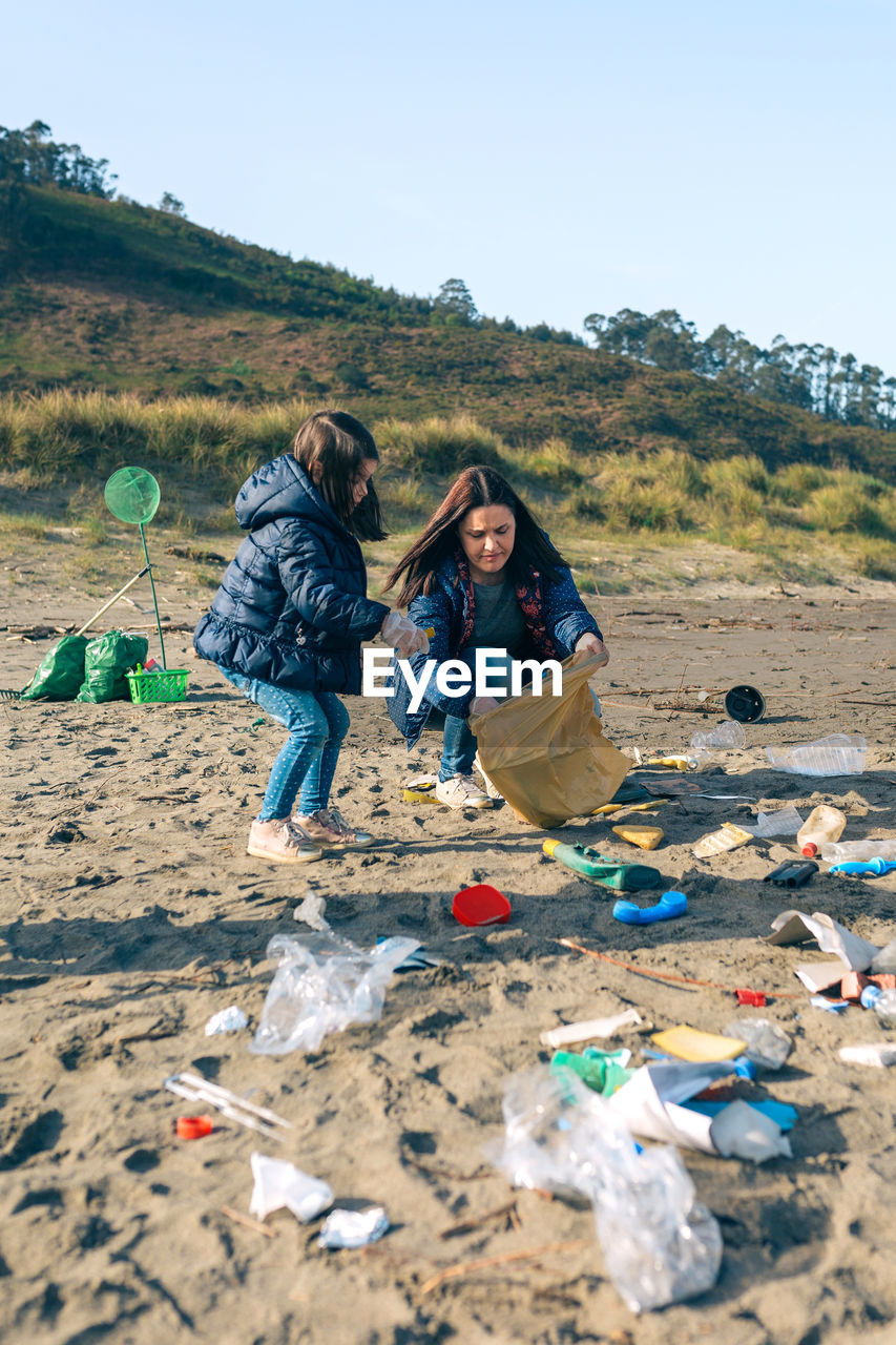 Mother and daughter picking garbage at beach