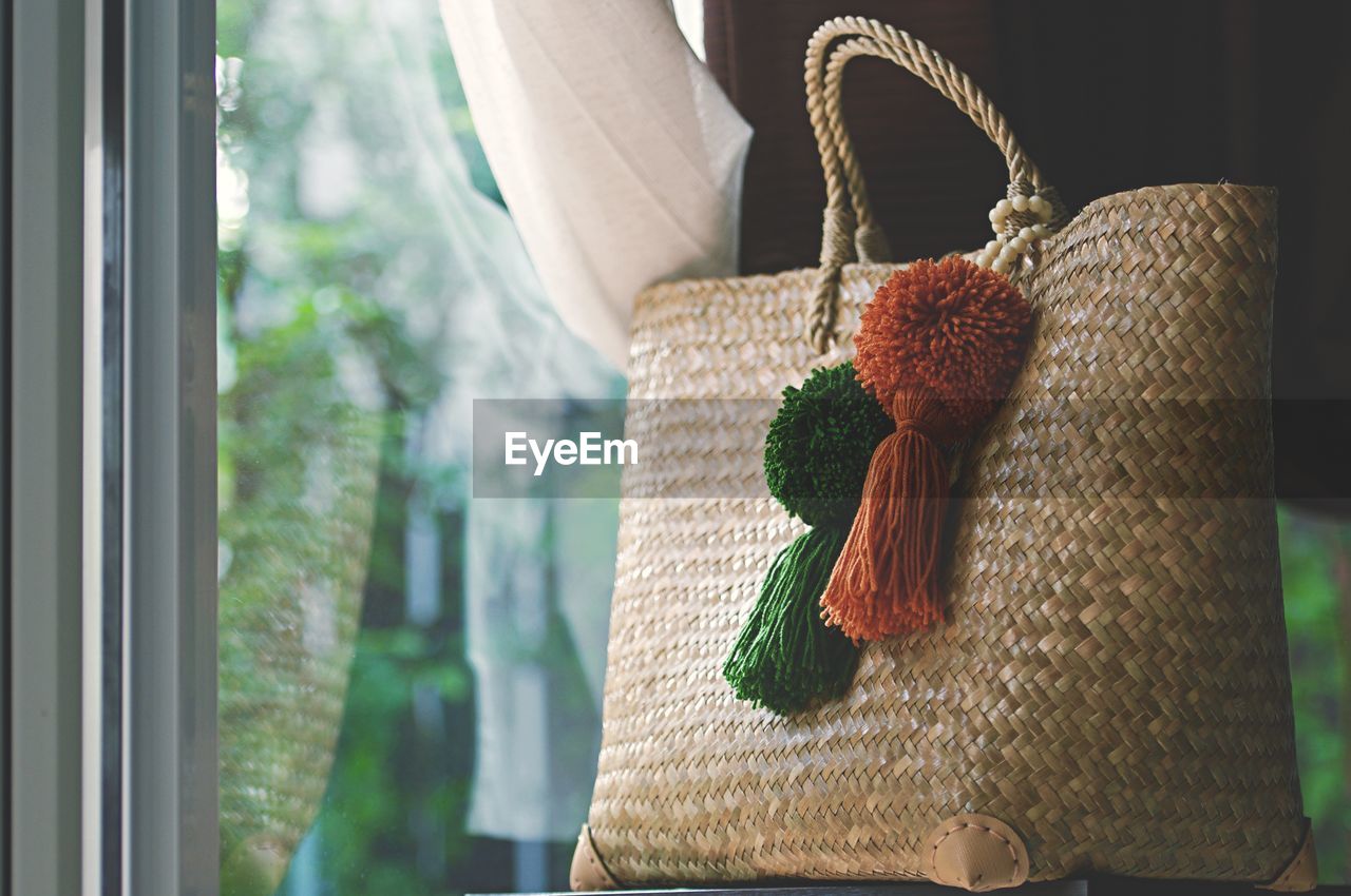 Close-up of wicker purse against window at home