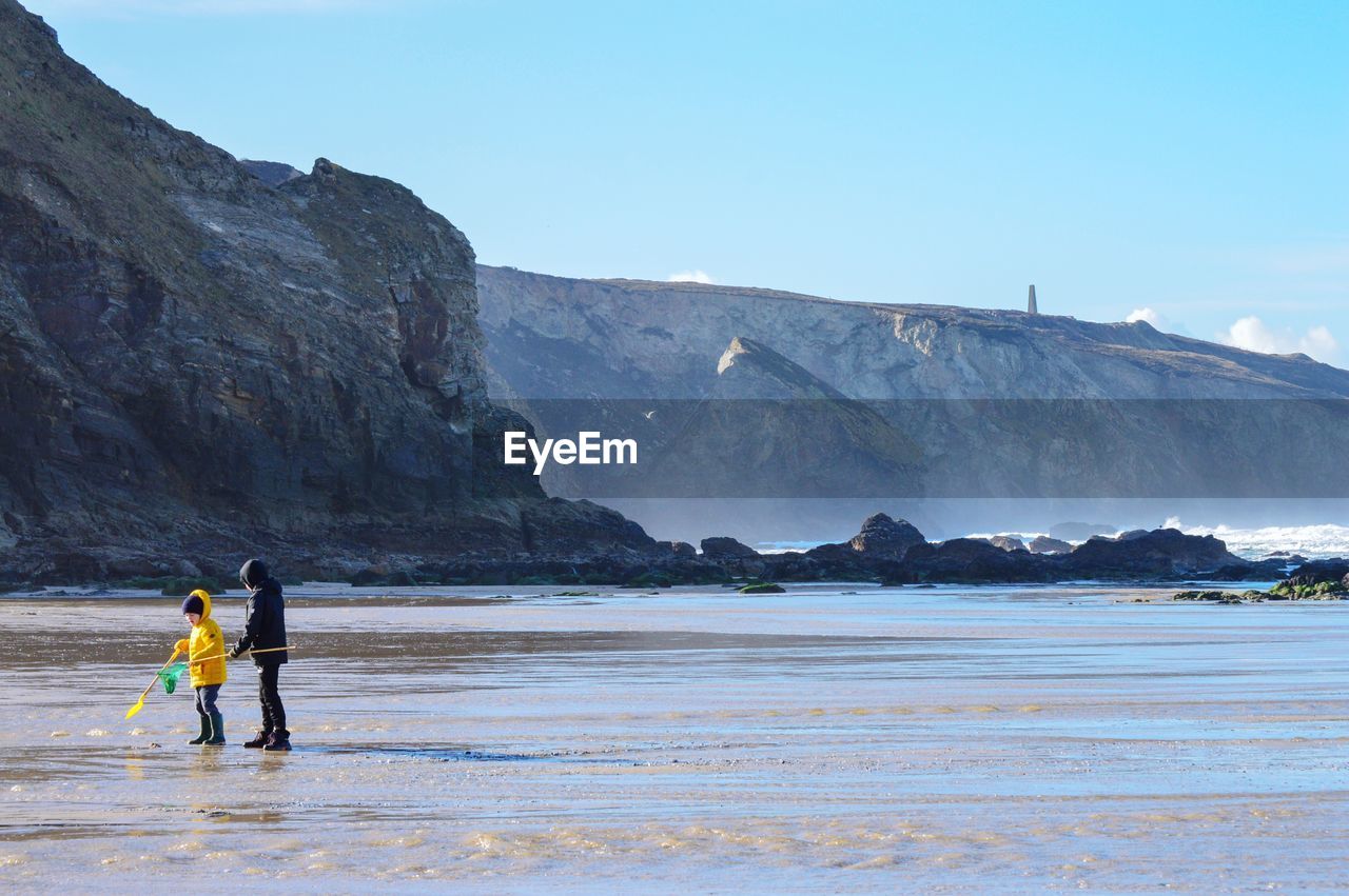 PEOPLE ON SHORE AGAINST MOUNTAINS