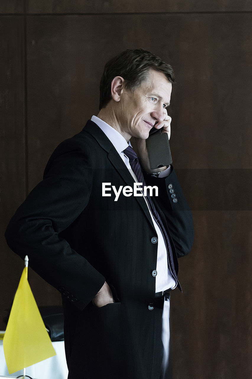 Businessman talking on phone while standing in office