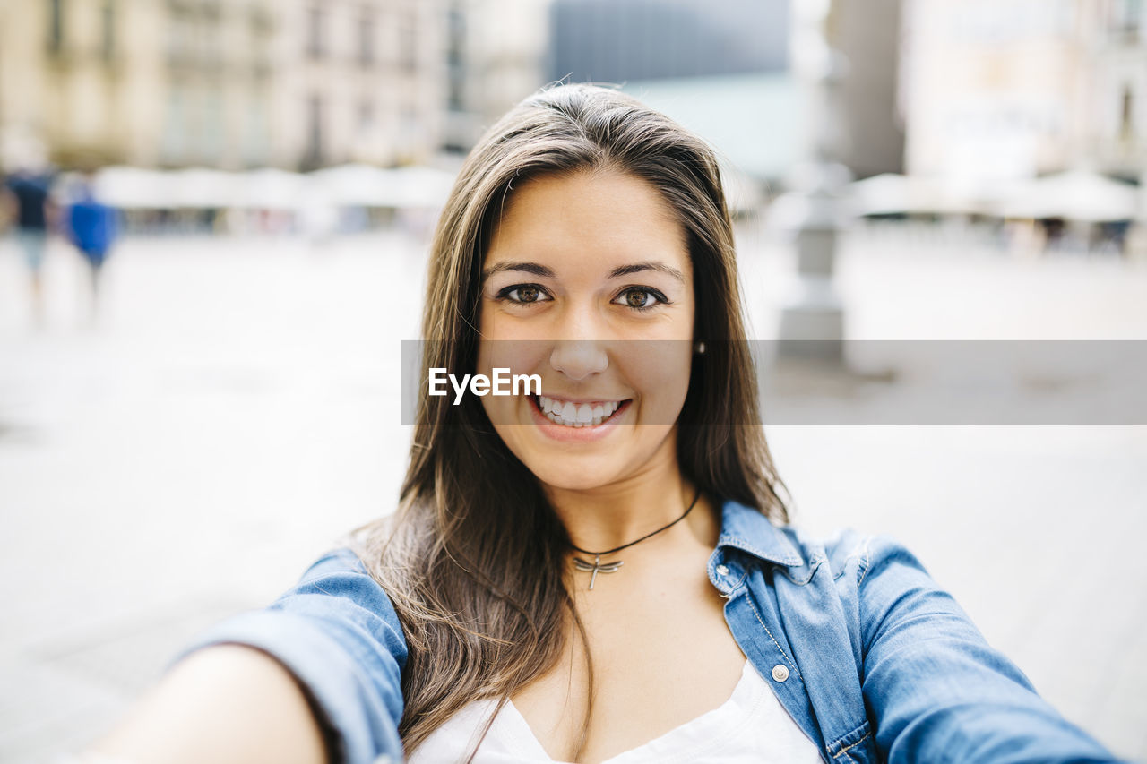 Portrait of smiling young woman standing in city