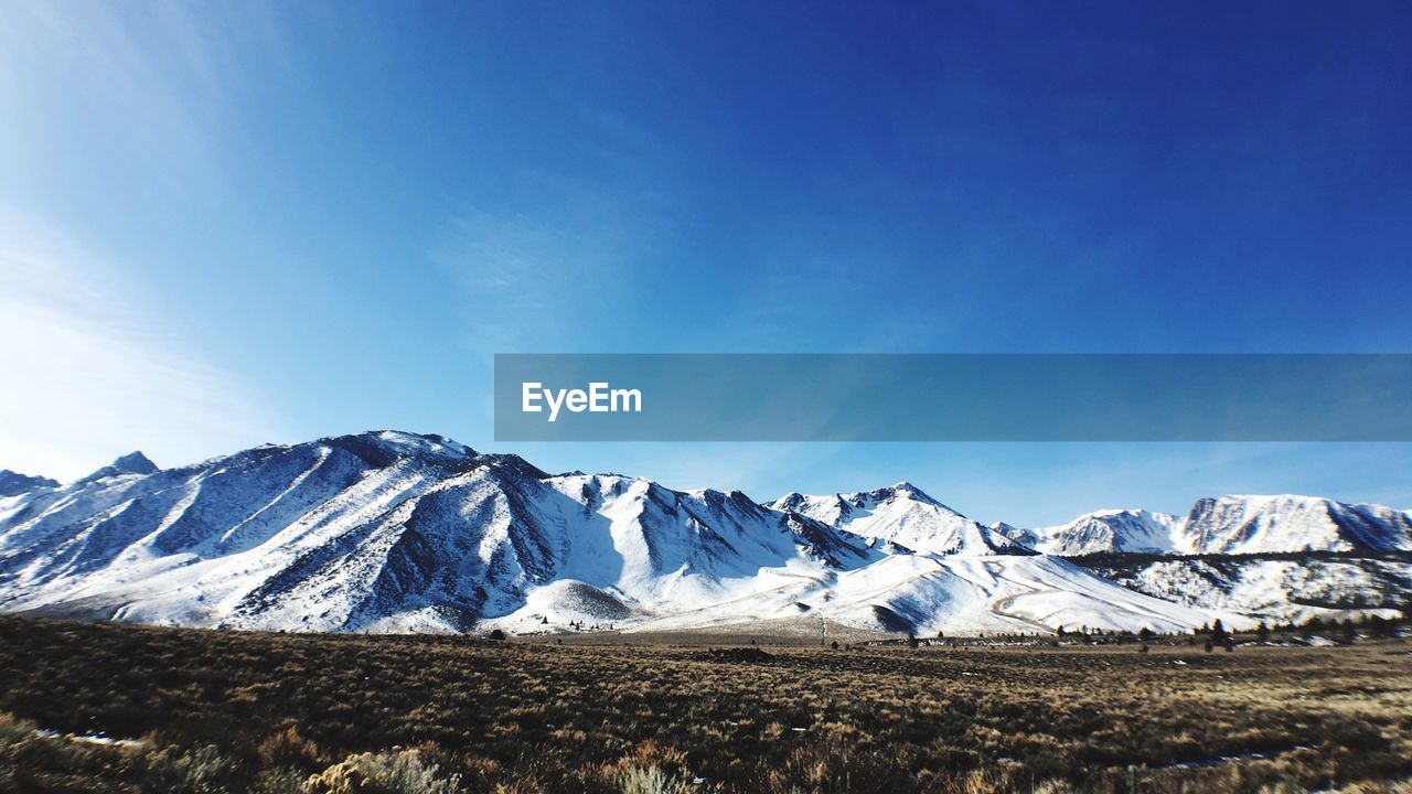 Scenic view of snowcapped mountains against blue sky