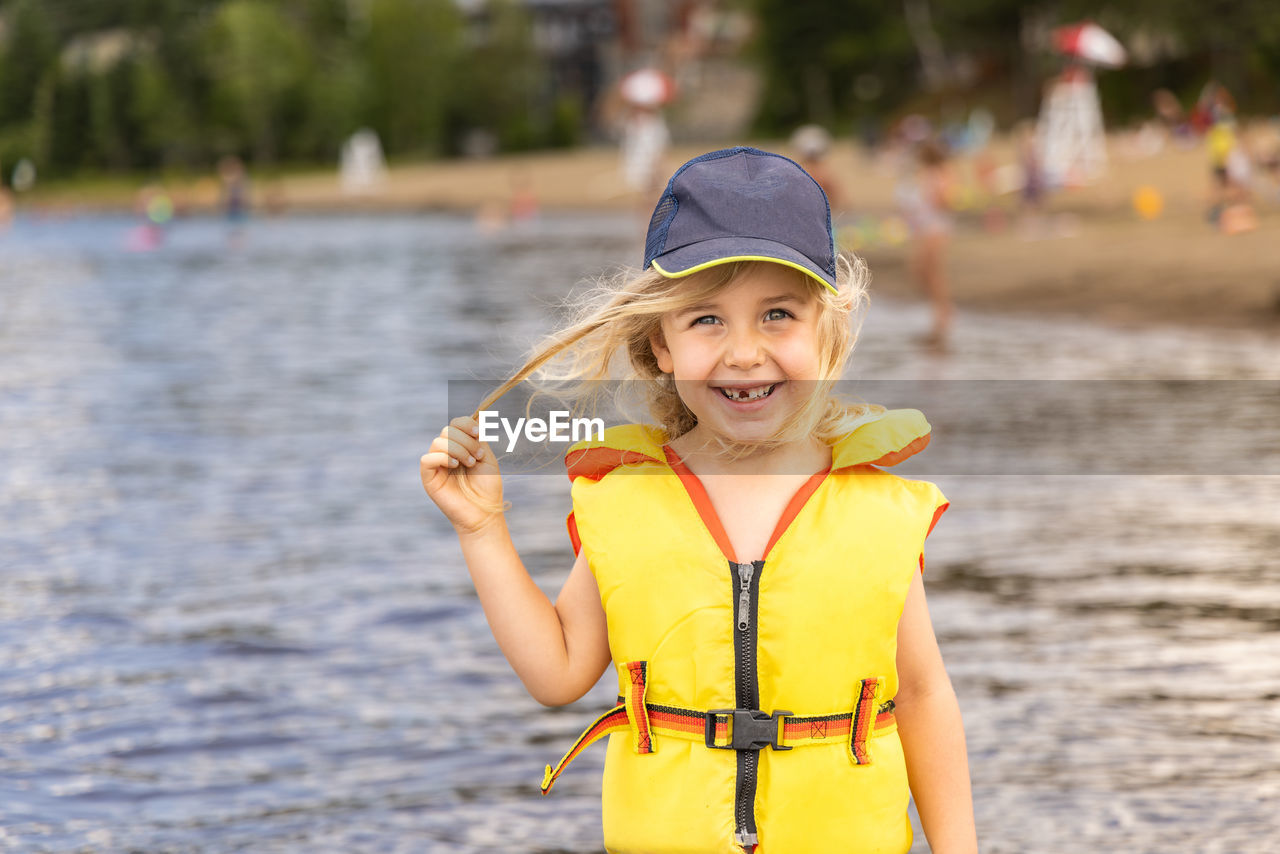 portrait of young woman wearing hat while standing in lake