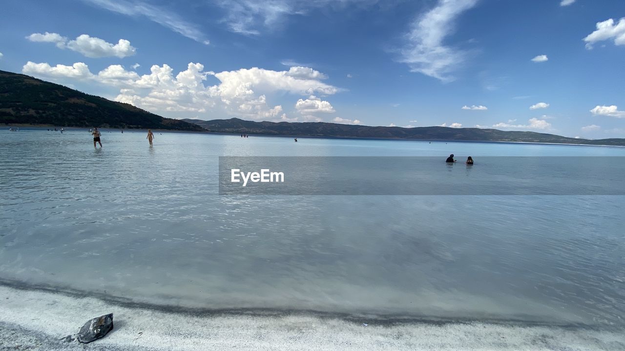 PEOPLE ENJOYING ON BEACH AGAINST SKY