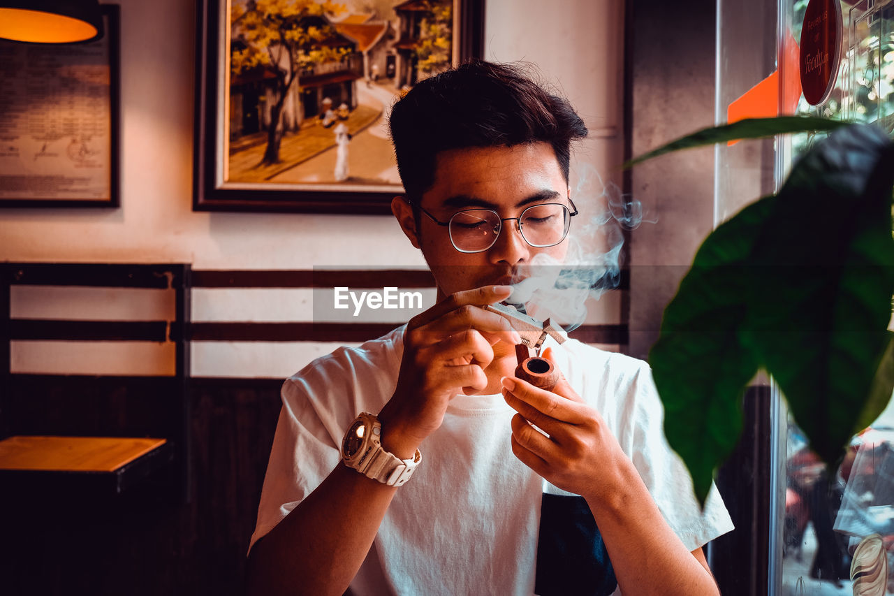 Man smoking pipe cigarette at home