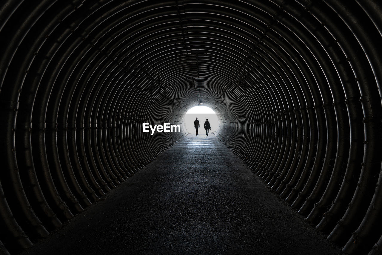 Rear view of silhouette man walking in tunnel