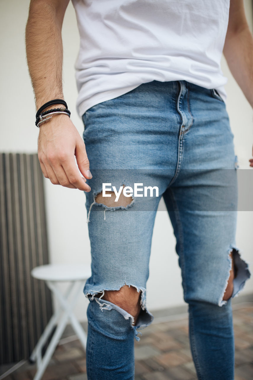 Close-up picture of attractive guy with ripped jeans.