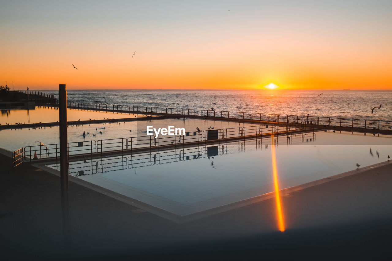 High angle view of swimming pool by sea during sunset