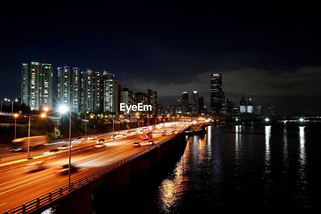 ILLUMINATED CITY BY BUILDINGS AT NIGHT