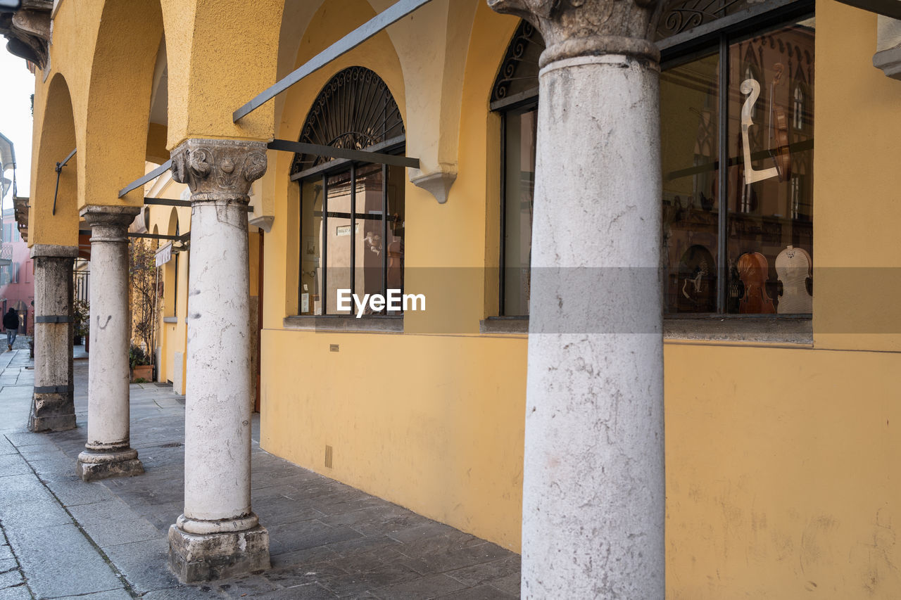 Ancient columns and arches and a luthier's store near the cathedral of cremona, lombardy - italy.