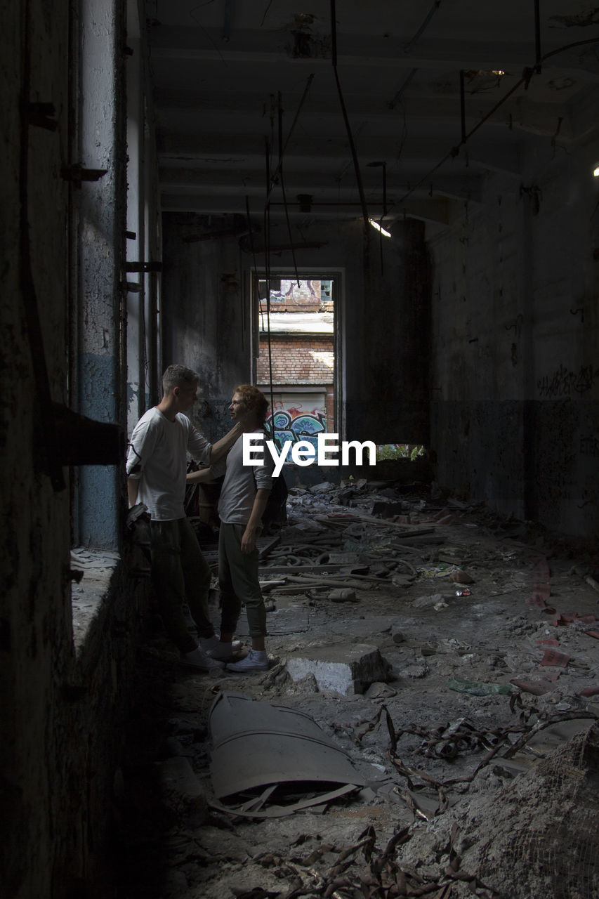 FULL LENGTH REAR VIEW OF MAN STANDING IN ABANDONED BUILDING