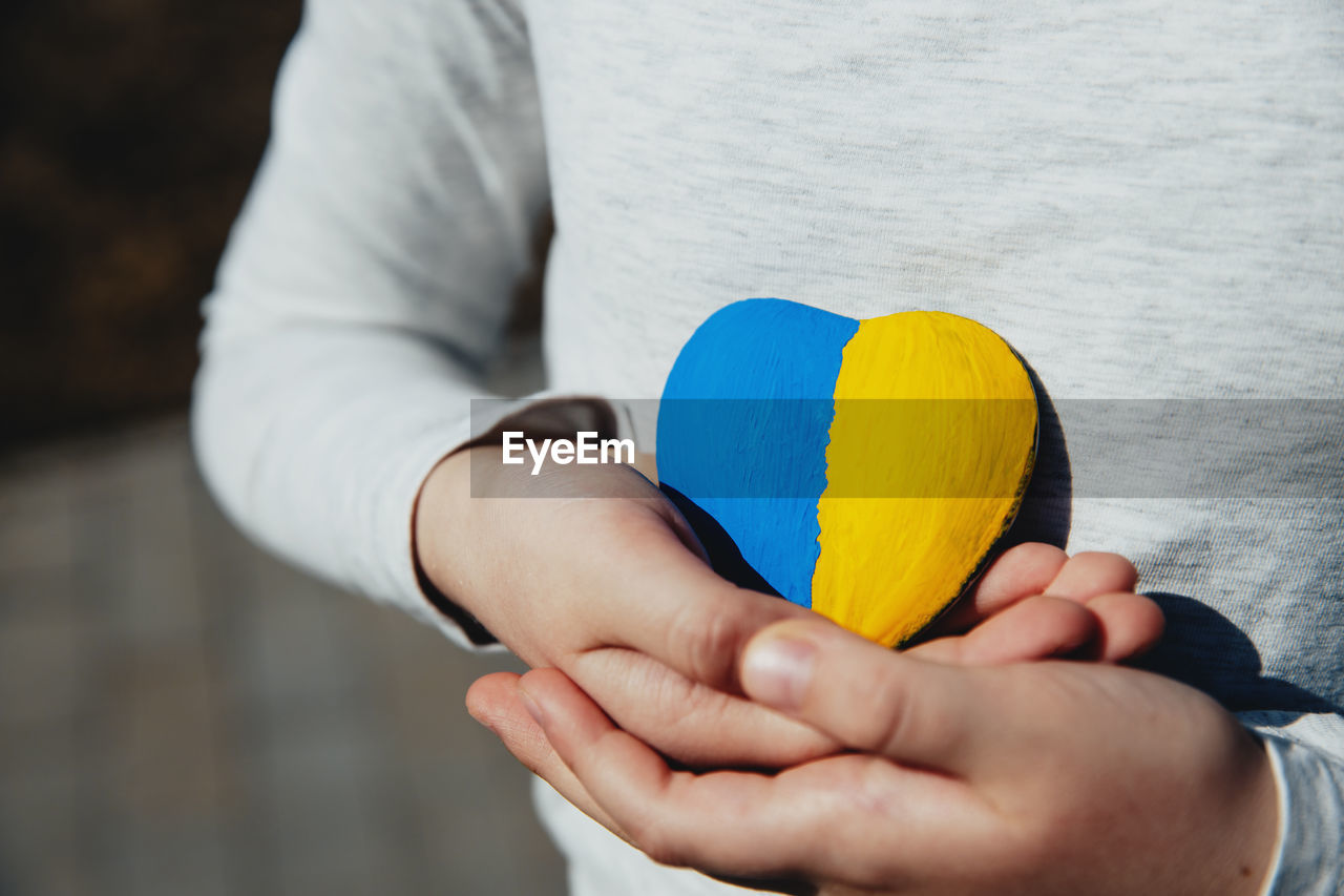 Small little kid hold heart with ukraine flag. child stand for ukrainians. stop war, agression
