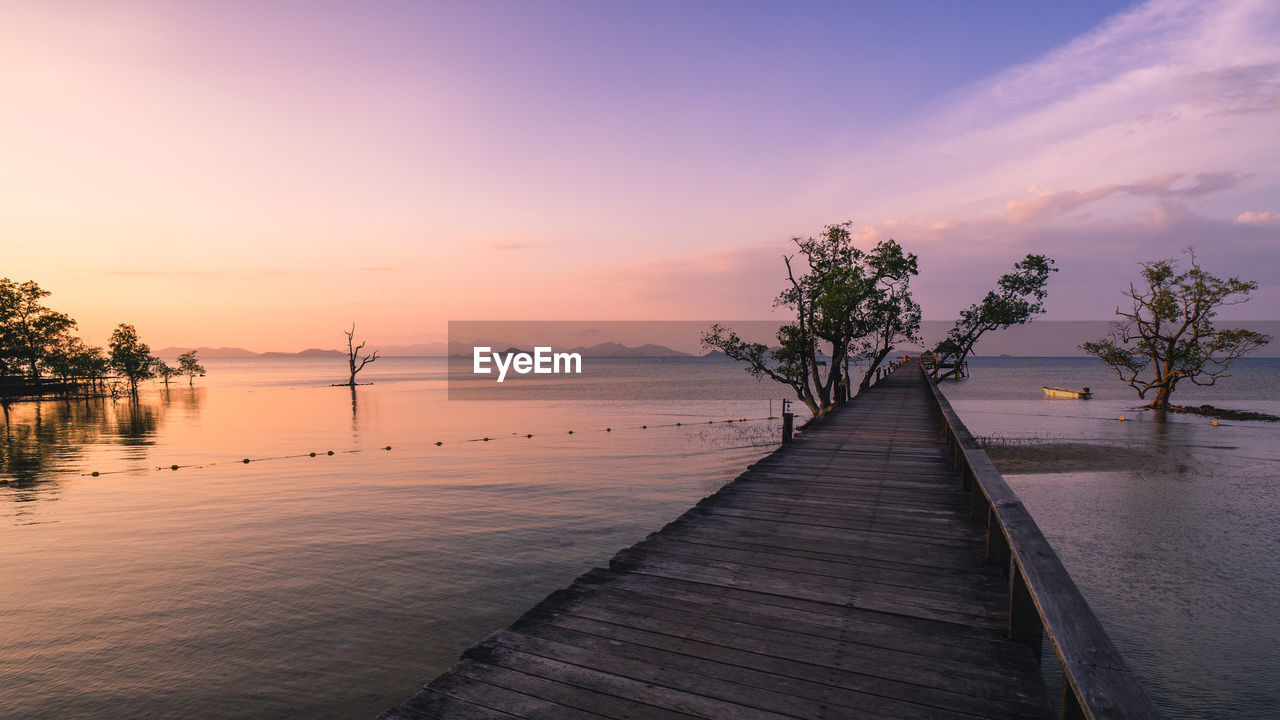 water, sky, sunset, sea, beauty in nature, nature, scenics - nature, tranquility, evening, tree, dusk, land, environment, beach, horizon, reflection, landscape, tranquil scene, shore, travel destinations, plant, cloud, pier, sun, travel, seascape, tropical climate, wood, trip, vacation, holiday, idyllic, horizon over water, twilight, outdoors, architecture, relaxation, coast, palm tree, sunlight, summer, no people, ocean, tourism, jetty, blue, coastline, footpath, romantic sky, orange color, transportation, non-urban scene, island, silhouette, igniting, urban skyline, lagoon, nautical vessel, sand, multi colored