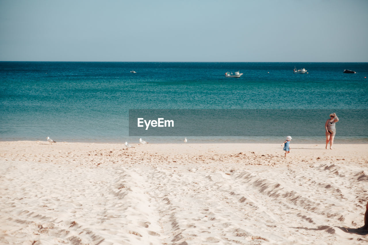 PEOPLE AT BEACH AGAINST SKY