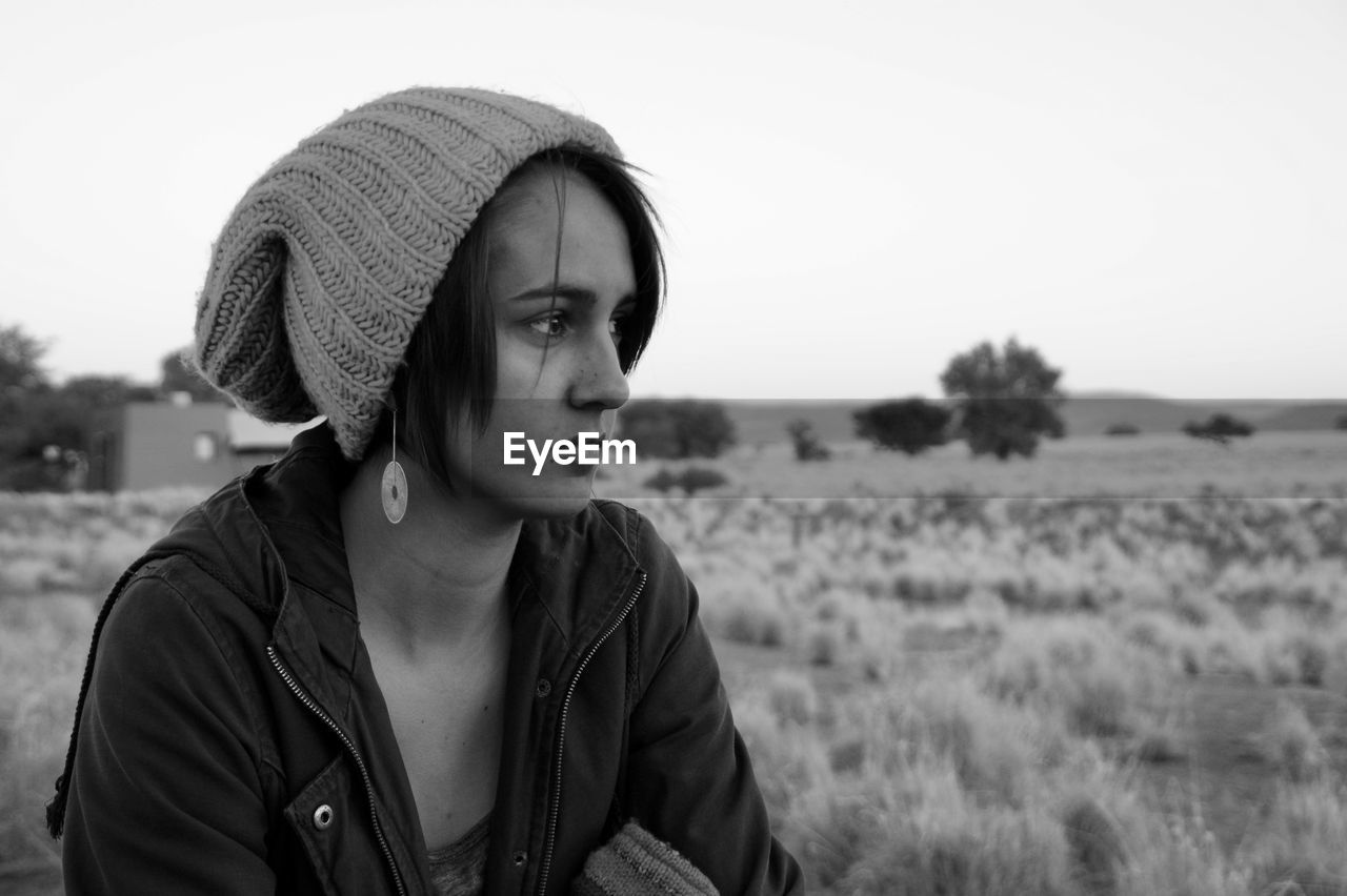 Portrait of young woman looking away on field