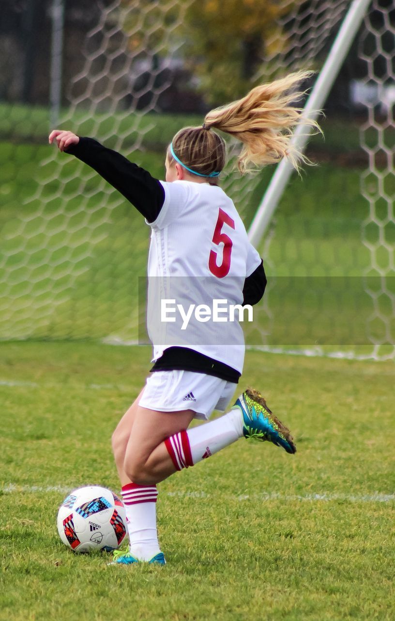 LOW SECTION OF WOMAN PLAYING SOCCER BALL