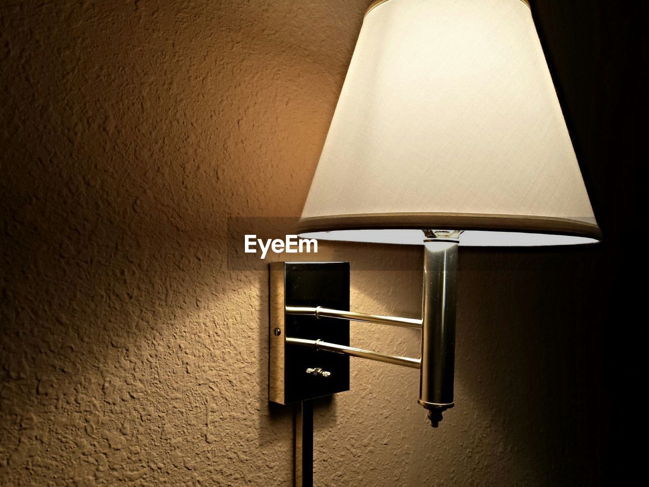 Illuminated lamp mounted on wall at home