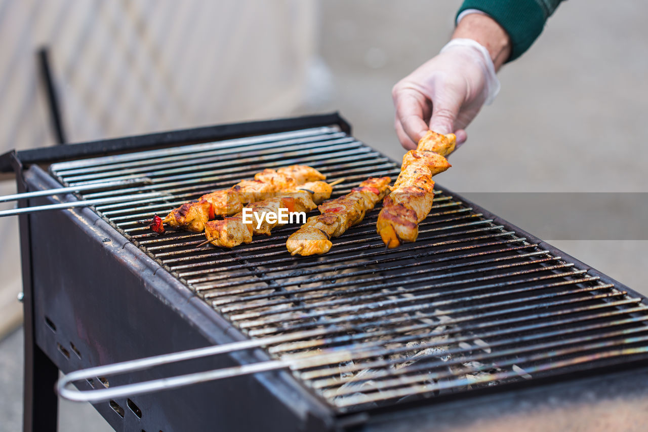 MIDSECTION OF MAN PREPARING FOOD ON BARBECUE