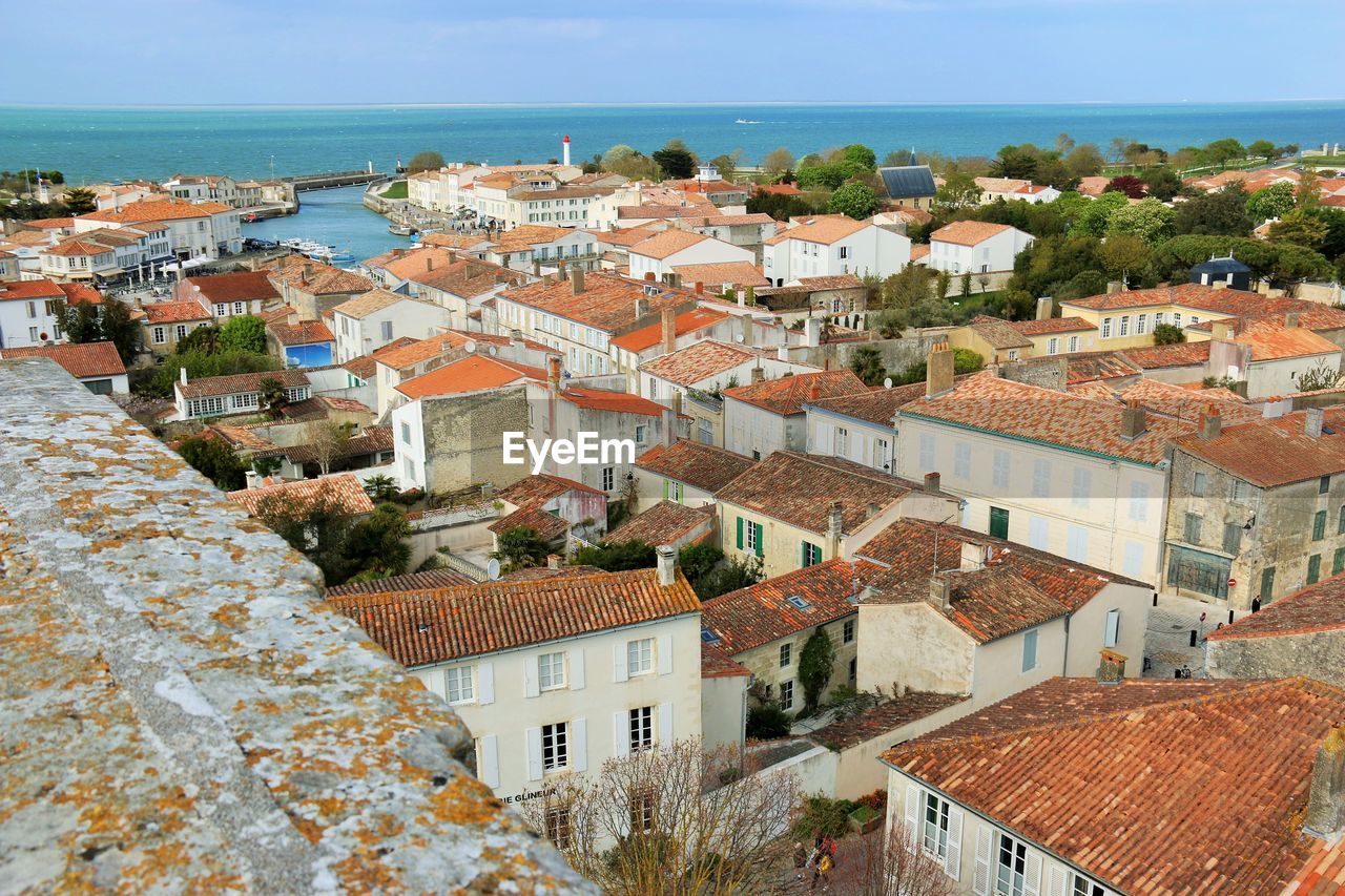 High angle view of townscape by sea against sky