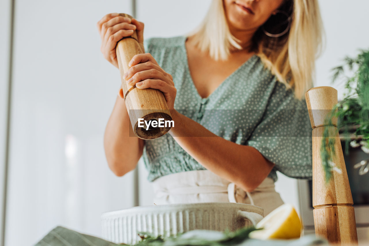 Woman in the kitchen grinding pepper to food