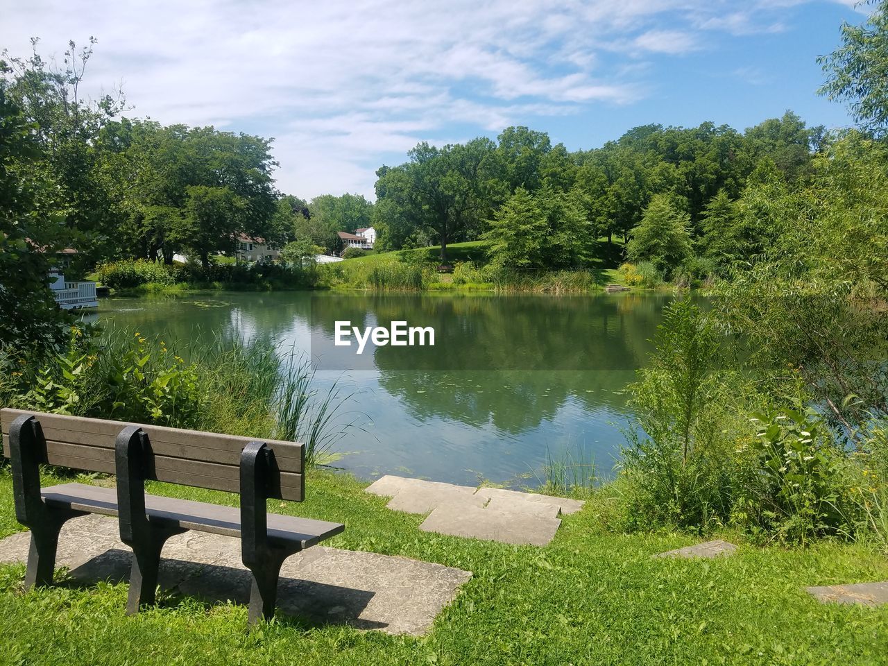 Scenic view of park by lake against sky