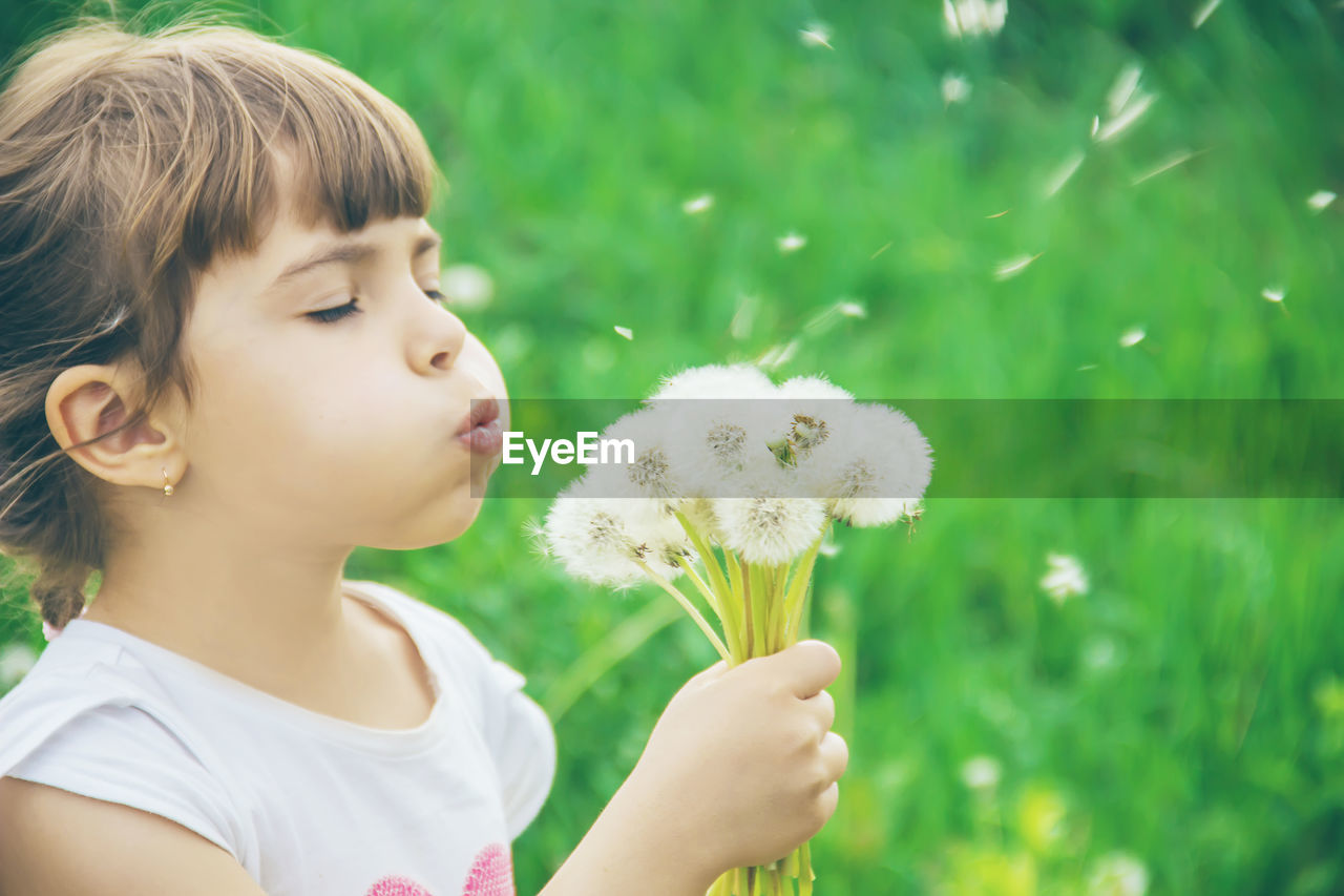 close-up of young woman blowing dandelion