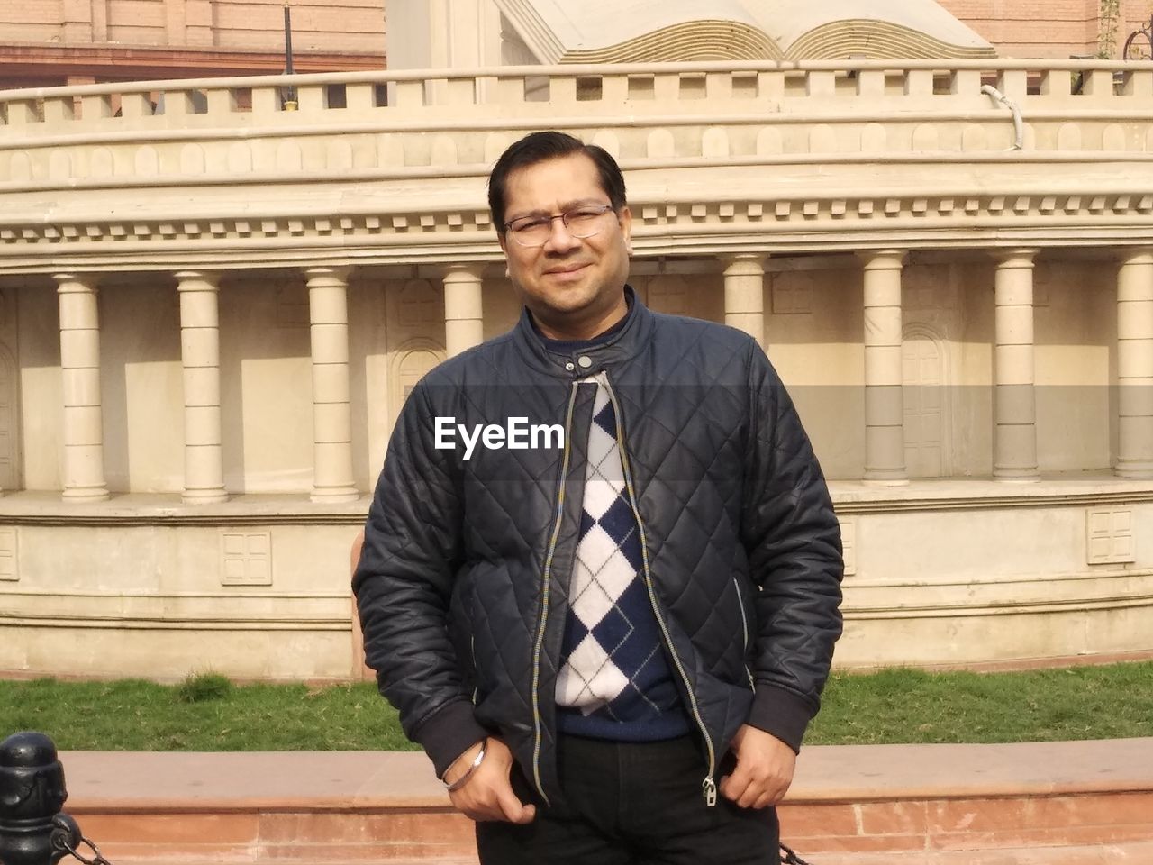 Portrait of smiling mid adult man standing against building