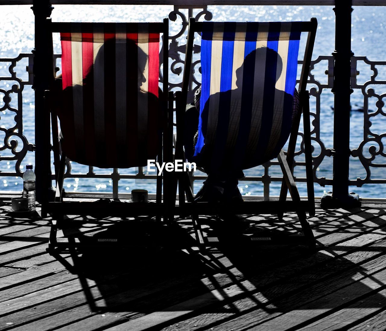 Man and woman resting on deck chairs at pier