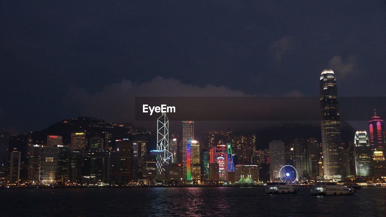 Illuminated buildings in city against sky at night