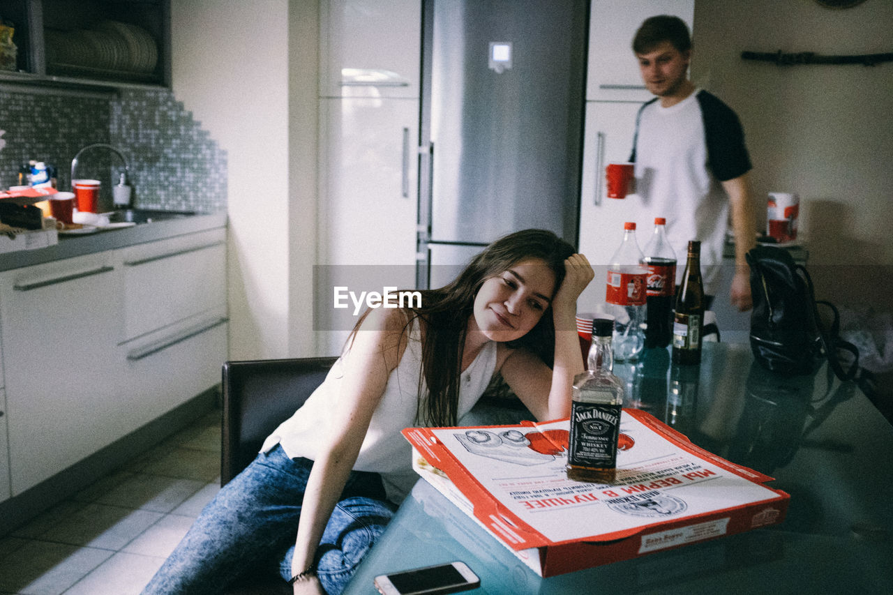 YOUNG WOMAN LOOKING DOWN WHILE SITTING ON TABLE