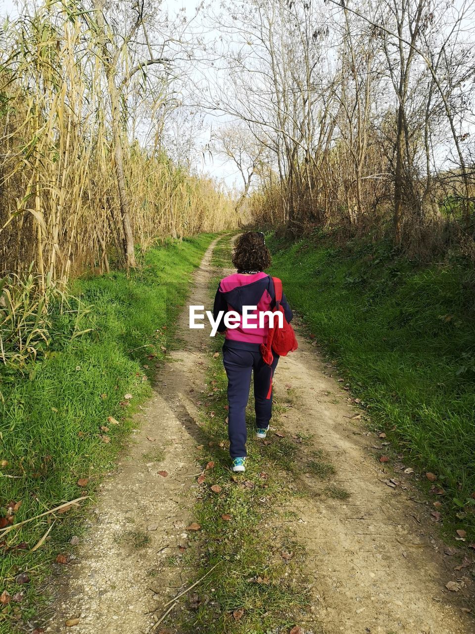 FULL LENGTH REAR VIEW OF WOMAN WALKING ON FOOTPATH