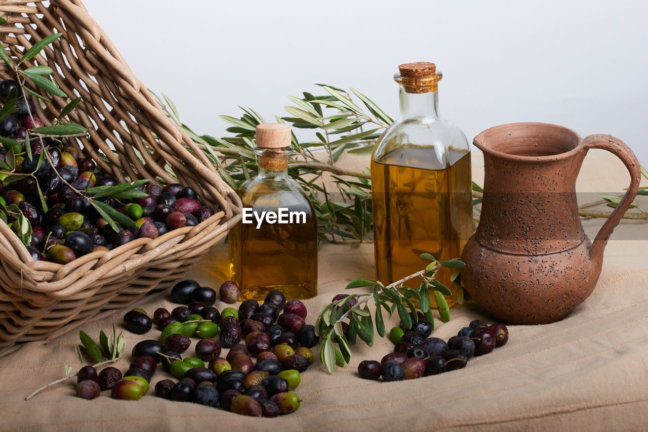 Striking oil bottles surrounded by several ripe olives