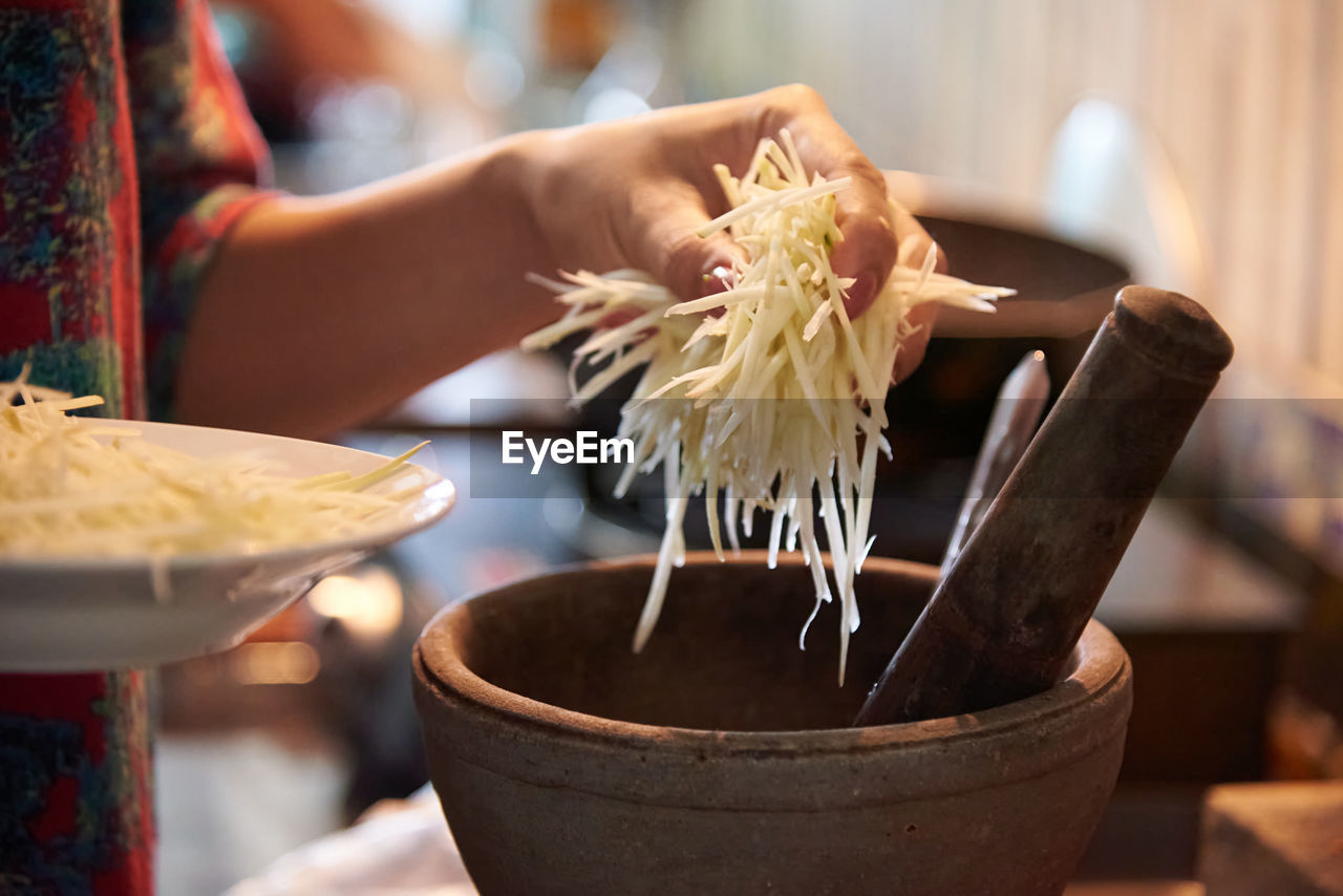 Chef putting the sliced green papaya to the mortar