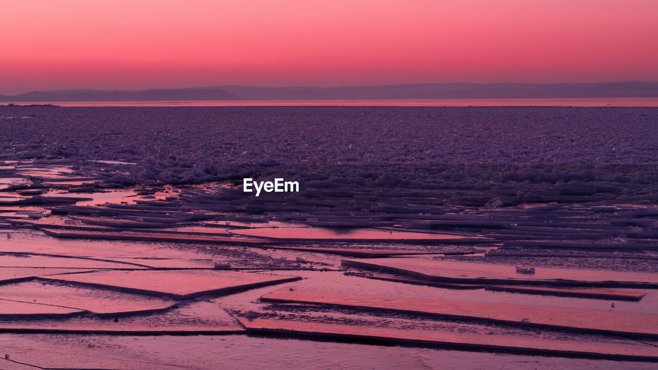 Scenic view of frozen sea against orange sky during sunset