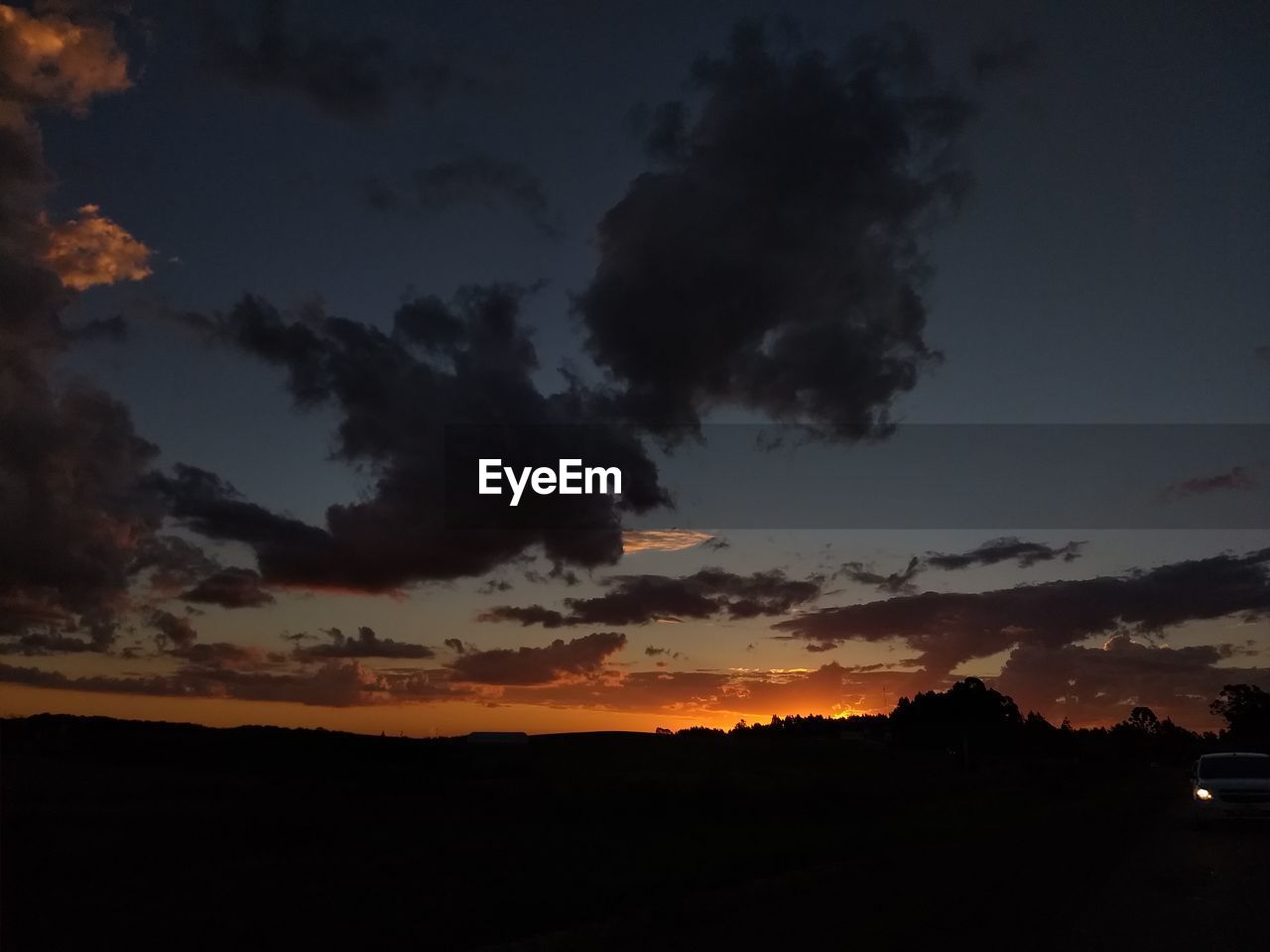 Silhouette landscape against dramatic sky during sunset