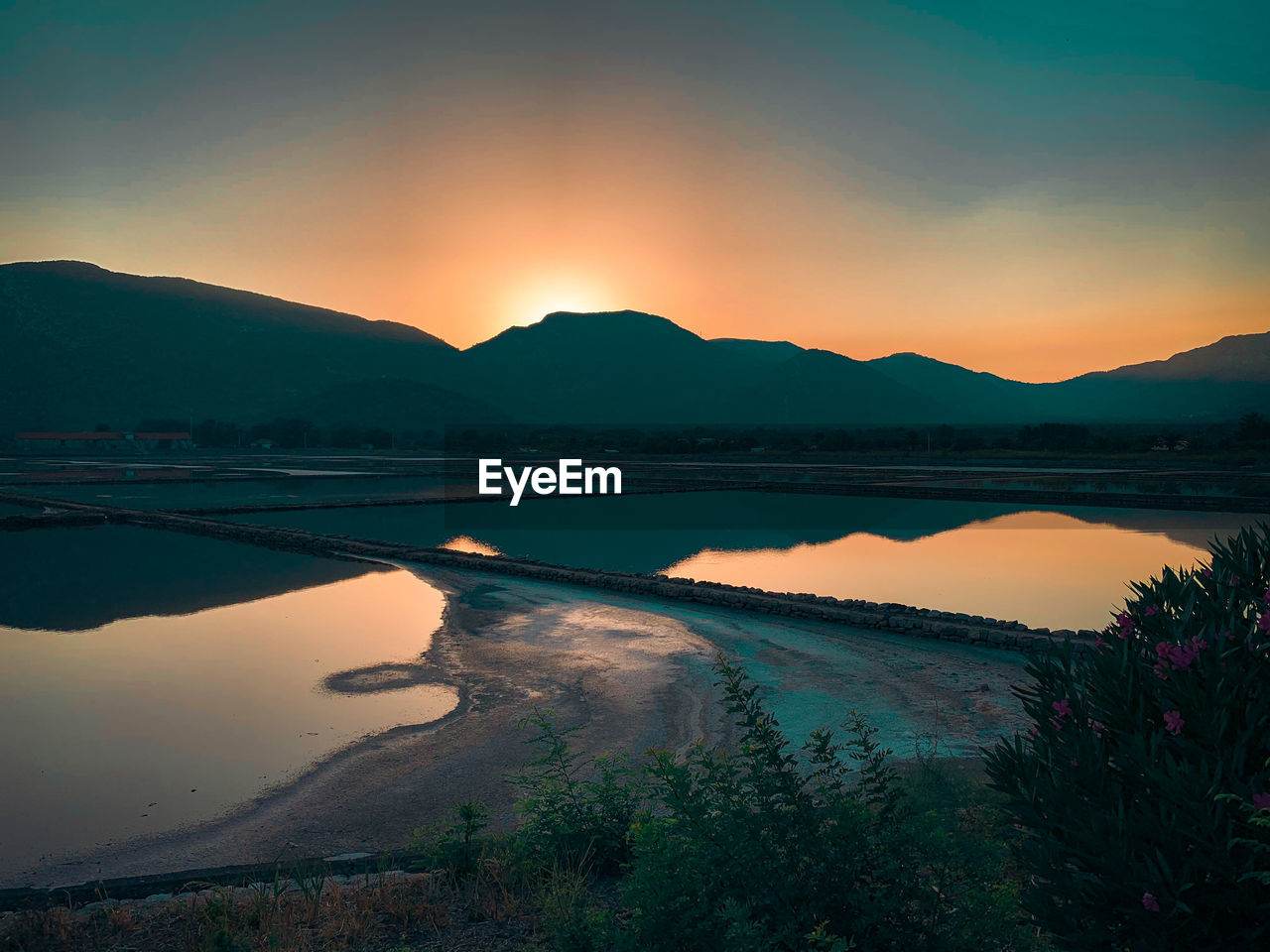 Scenic view of earth salt ponds against sky during sunset