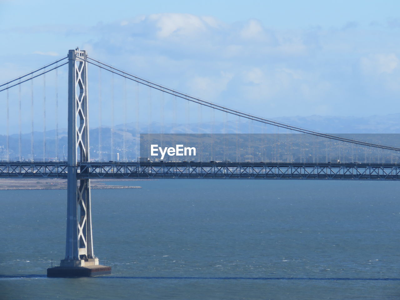 Bay bridge over sea against sky on sunny day